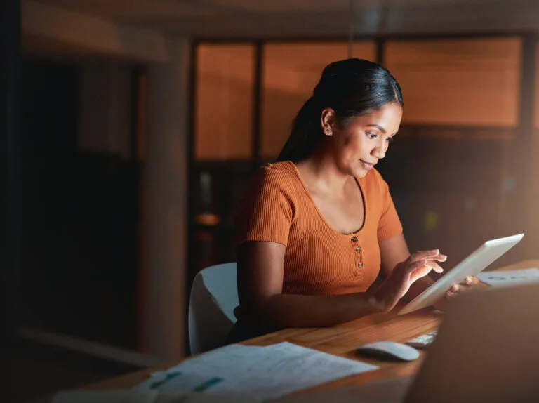 Shot of an attractive young businesswoman sitting alone in the office at night and using a digital tablet